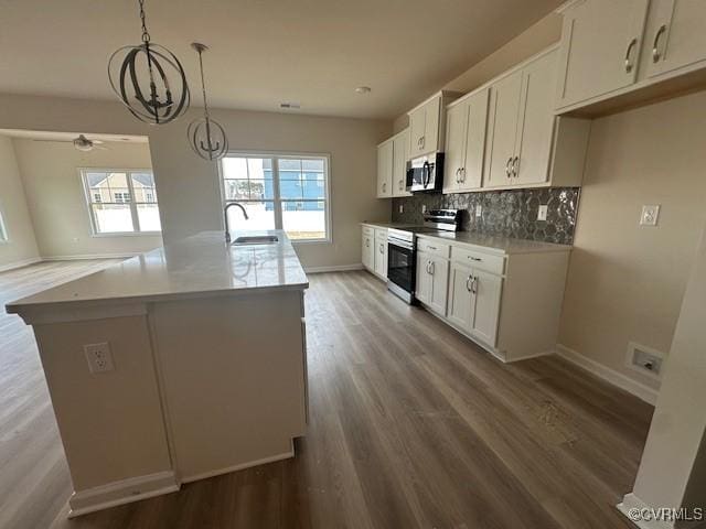 kitchen with a center island with sink, white cabinetry, appliances with stainless steel finishes, and pendant lighting