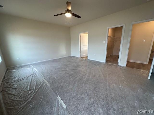 unfurnished bedroom featuring a walk in closet and ceiling fan