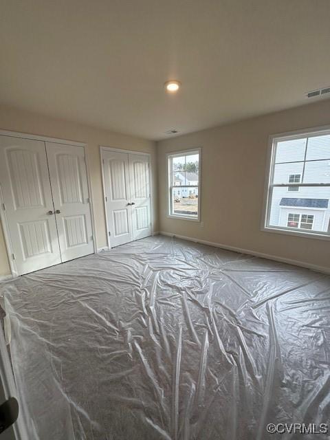 unfurnished bedroom featuring two closets and light colored carpet