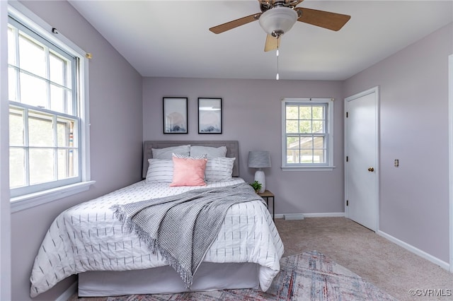 carpeted bedroom with multiple windows, a ceiling fan, and baseboards