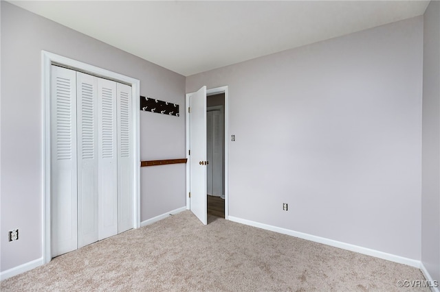 unfurnished bedroom with carpet flooring, baseboards, and a closet