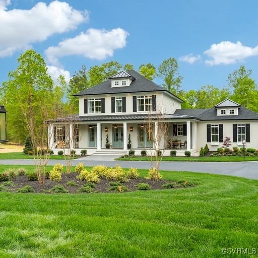 view of front facade featuring a front lawn, a porch, french doors, metal roof, and a standing seam roof