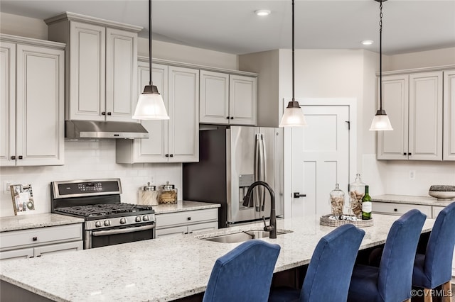 kitchen featuring pendant lighting, stainless steel appliances, a center island with sink, and sink