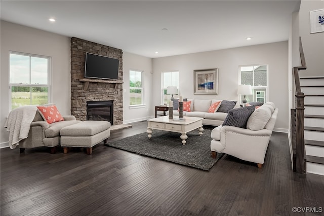 living room featuring plenty of natural light, dark hardwood / wood-style flooring, and a stone fireplace