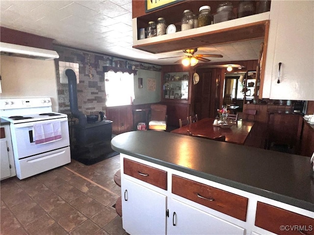 kitchen with ceiling fan, dark countertops, white cabinetry, white range with electric stovetop, and a wood stove
