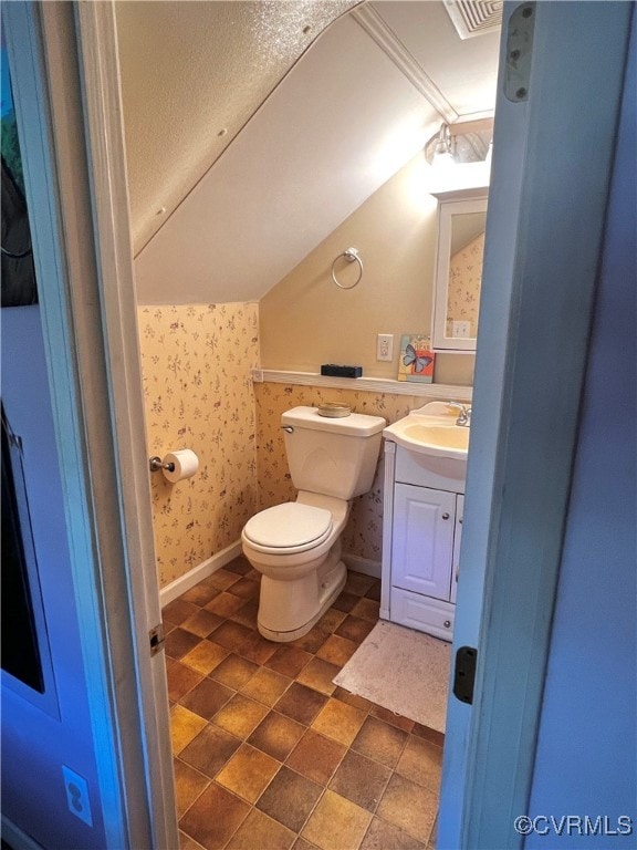 bathroom with vanity, toilet, and vaulted ceiling