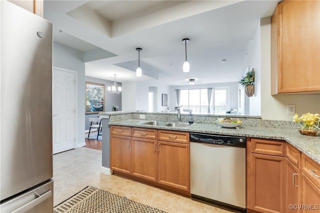 kitchen with appliances with stainless steel finishes, light stone countertops, kitchen peninsula, and sink