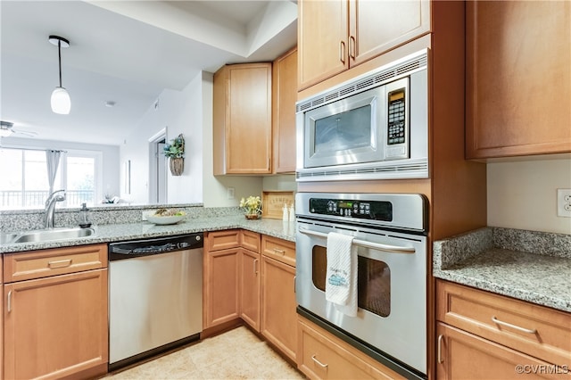 kitchen featuring appliances with stainless steel finishes, light stone countertops, sink, and pendant lighting