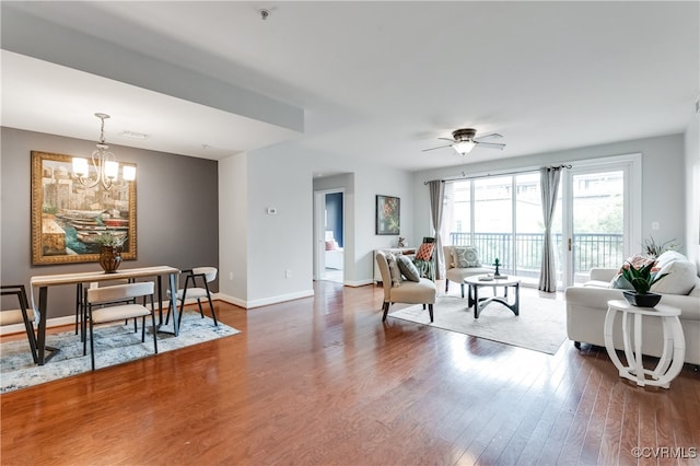 living room featuring ceiling fan with notable chandelier and dark hardwood / wood-style floors