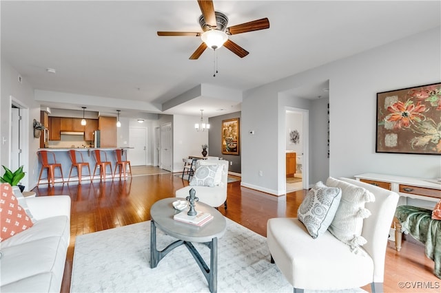 living room with light wood-type flooring and ceiling fan with notable chandelier