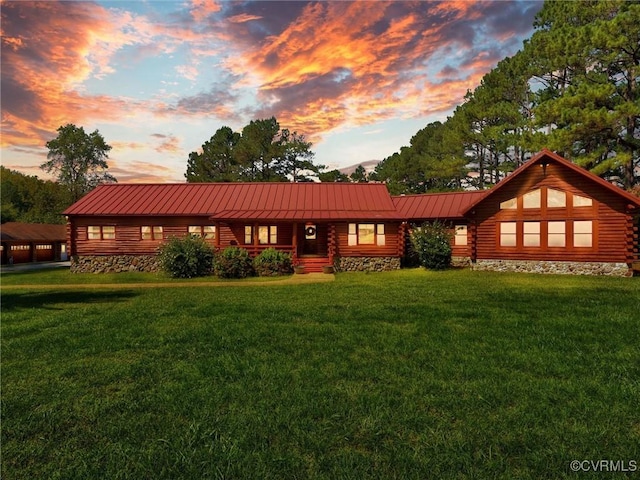 log-style house featuring a lawn, metal roof, a standing seam roof, and log exterior