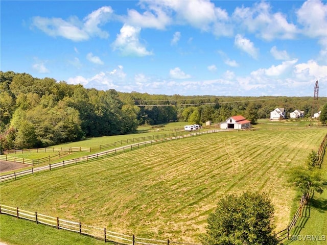 view of yard with an outdoor structure, fence, a rural view, and a wooded view