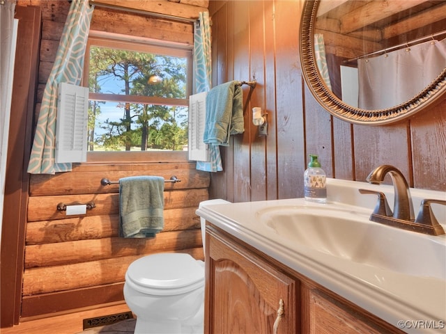 bathroom featuring vanity, rustic walls, and toilet