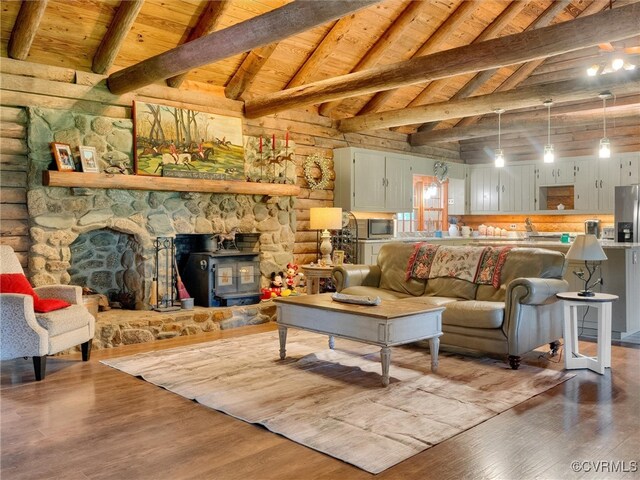 living room featuring wood-type flooring, a wood stove, beam ceiling, a fireplace, and wooden ceiling