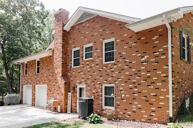 view of property exterior with a garage and central AC unit