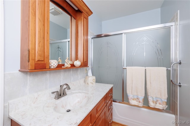 bathroom featuring vanity, decorative backsplash, and enclosed tub / shower combo