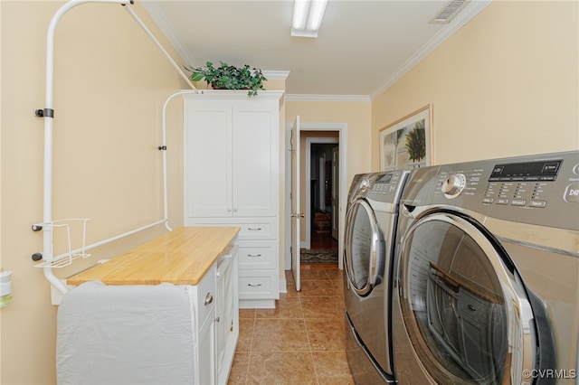 laundry area with ornamental molding, light tile patterned floors, cabinets, and washer and dryer