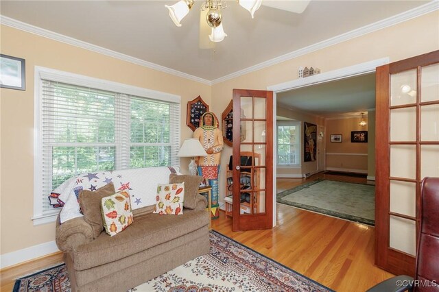 living room featuring crown molding, plenty of natural light, wood-type flooring, and ceiling fan