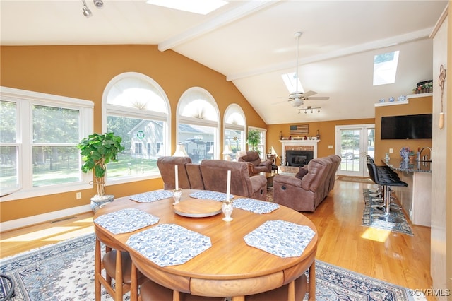 dining space with light wood-type flooring, french doors, ceiling fan, and lofted ceiling with skylight