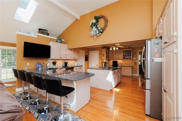 kitchen with appliances with stainless steel finishes, a center island, a breakfast bar, decorative backsplash, and a skylight