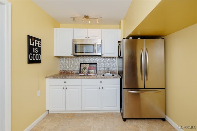 kitchen with stone counters, backsplash, stainless steel appliances, sink, and white cabinets