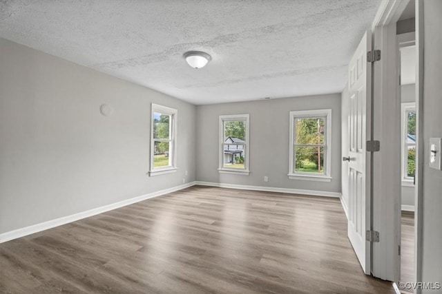 unfurnished room featuring hardwood / wood-style floors, a wealth of natural light, and a textured ceiling