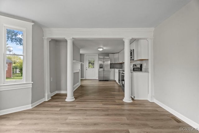 foyer featuring crown molding, light hardwood / wood-style flooring, and ornate columns