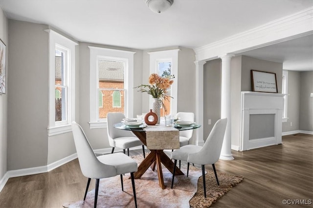 dining room featuring dark hardwood / wood-style flooring, a fireplace, and decorative columns