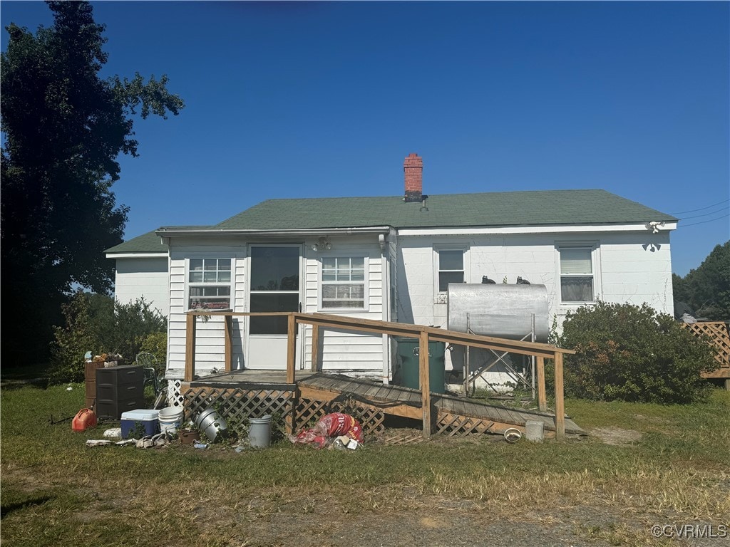 rear view of house with a lawn and a wooden deck