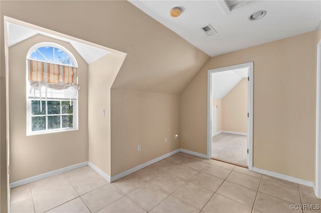 bonus room with lofted ceiling and light tile patterned flooring