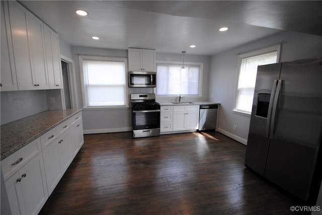 kitchen with appliances with stainless steel finishes, decorative light fixtures, sink, and white cabinets