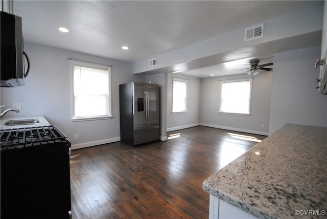 kitchen with light stone counters, stainless steel appliances, ceiling fan, dark hardwood / wood-style floors, and sink