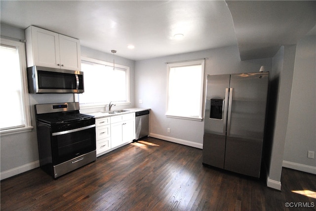 kitchen featuring white cabinets, hanging light fixtures, sink, appliances with stainless steel finishes, and dark hardwood / wood-style flooring