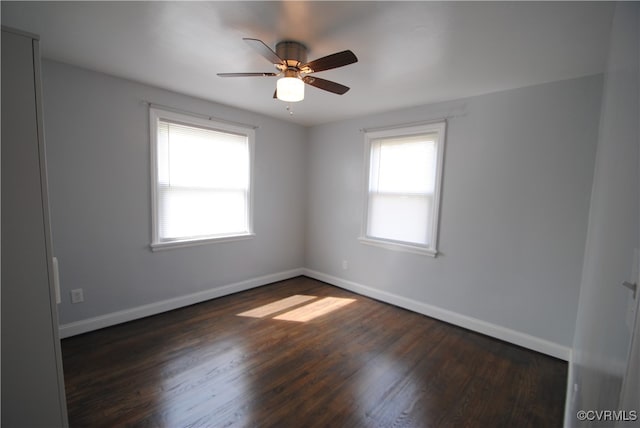 empty room featuring a healthy amount of sunlight, ceiling fan, and dark wood-type flooring