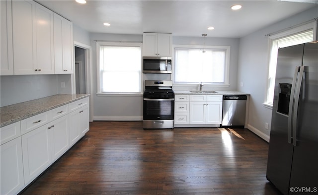 kitchen featuring pendant lighting, light stone counters, dark wood-type flooring, white cabinetry, and stainless steel appliances