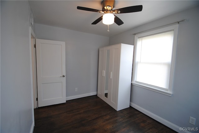 unfurnished bedroom featuring ceiling fan, dark hardwood / wood-style flooring, and multiple windows