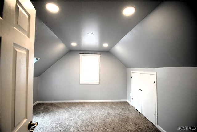 additional living space featuring vaulted ceiling and dark colored carpet