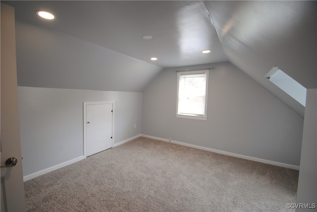 additional living space featuring vaulted ceiling with skylight and carpet