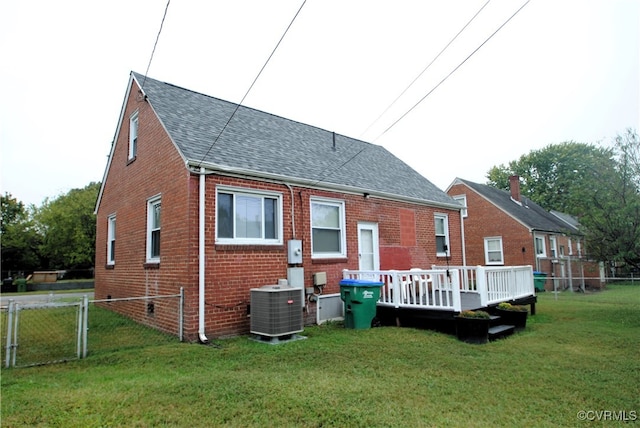 rear view of property with a lawn, a deck, and central AC unit