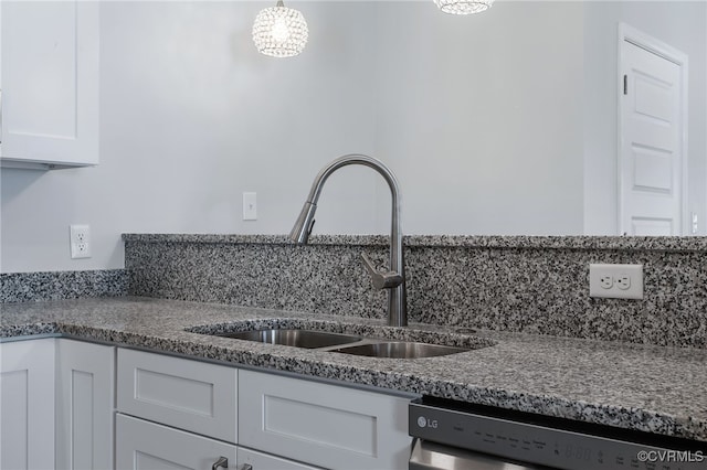 kitchen featuring stainless steel dishwasher, dark stone counters, sink, pendant lighting, and white cabinetry