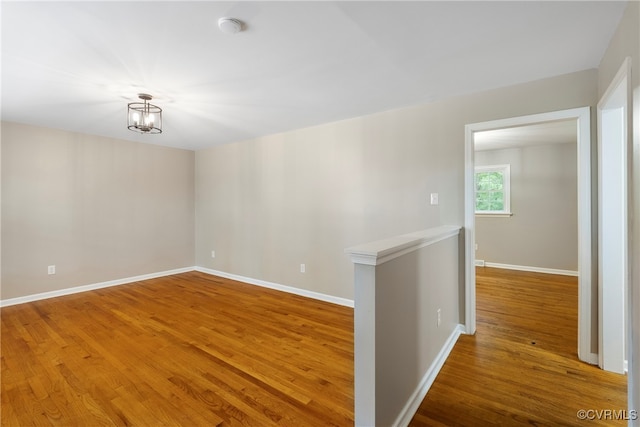 spare room featuring hardwood / wood-style flooring and a chandelier