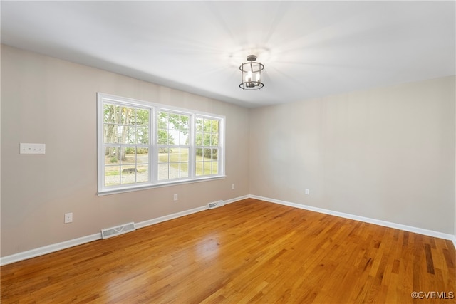 unfurnished room with an inviting chandelier and light wood-type flooring