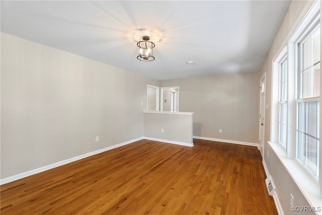 unfurnished room featuring a chandelier and hardwood / wood-style flooring