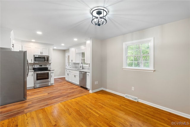 kitchen featuring appliances with stainless steel finishes, light hardwood / wood-style floors, and white cabinets