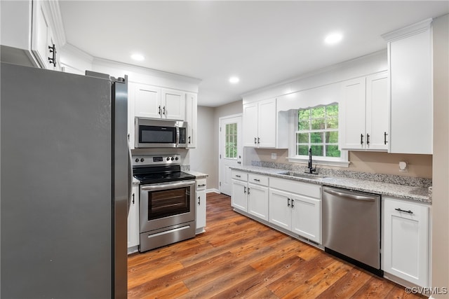 kitchen with wood-type flooring, appliances with stainless steel finishes, sink, and white cabinetry