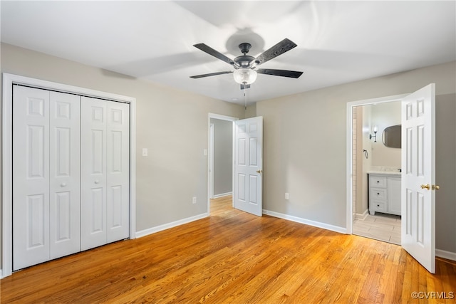 unfurnished bedroom featuring light hardwood / wood-style flooring, a closet, ceiling fan, and ensuite bathroom