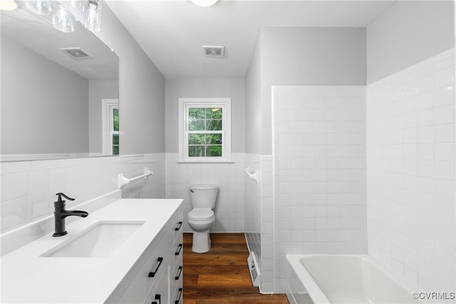 bathroom featuring vanity, tile walls, hardwood / wood-style floors, and toilet