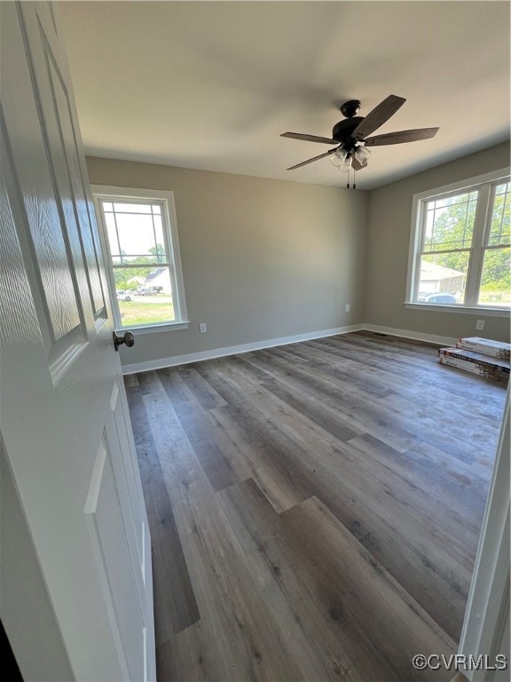 spare room featuring wood-type flooring, ceiling fan, and plenty of natural light