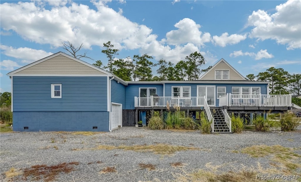 rear view of house featuring a deck and a garage