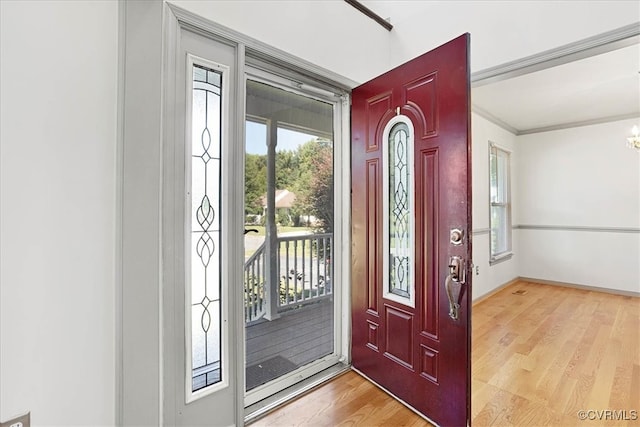 foyer featuring light wood-type flooring and crown molding